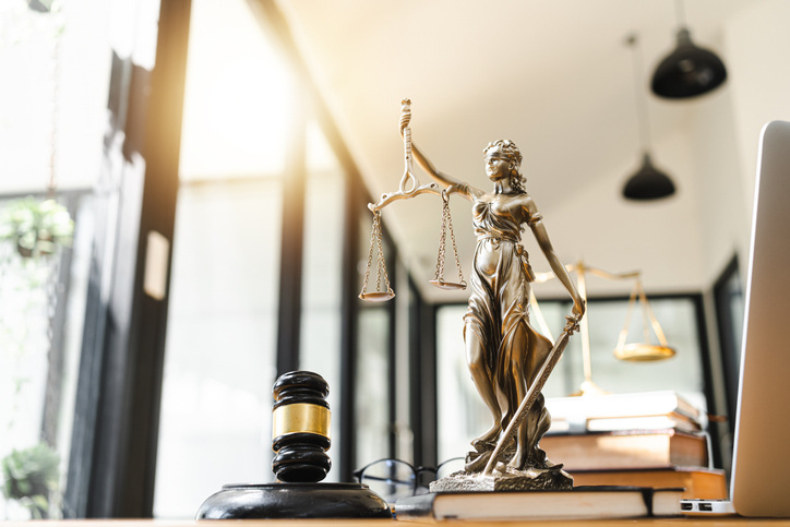 Statue of justice holding scale and sword with gavel on table